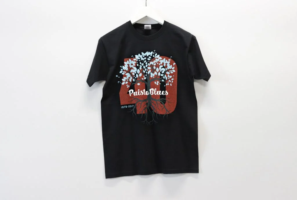 Mustassa t-paidassa on puuaiheinen PuistoBlues-painatus.